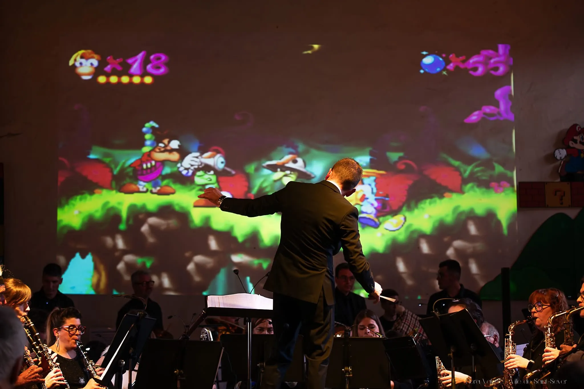 Julien Garcia dirigeant l'orchestre devant une projection géante du jeu vidéo Rayman
