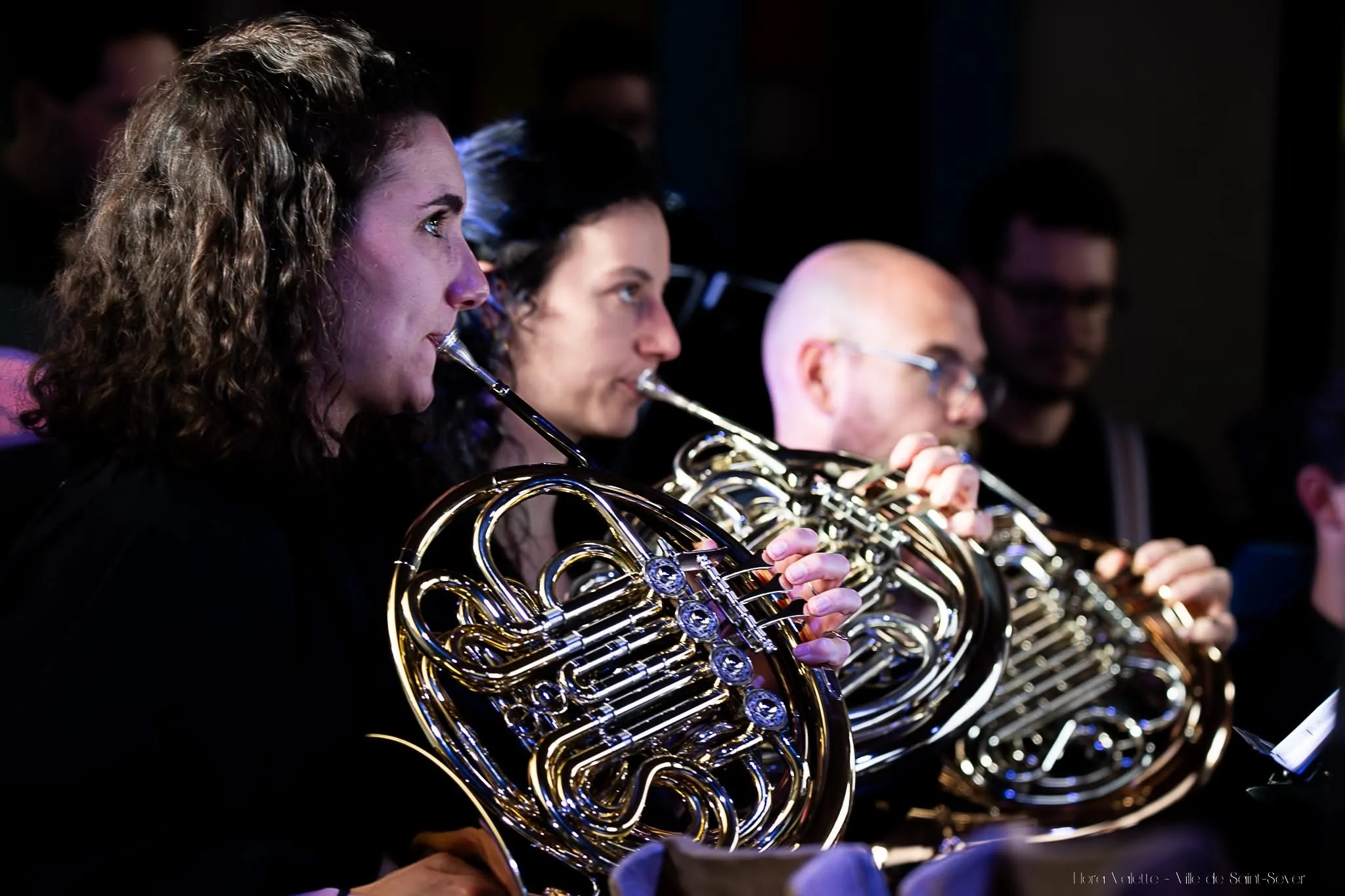 Trois cornistes de l'harmonie en train de jouer, gros plan sur les pavillons dorés