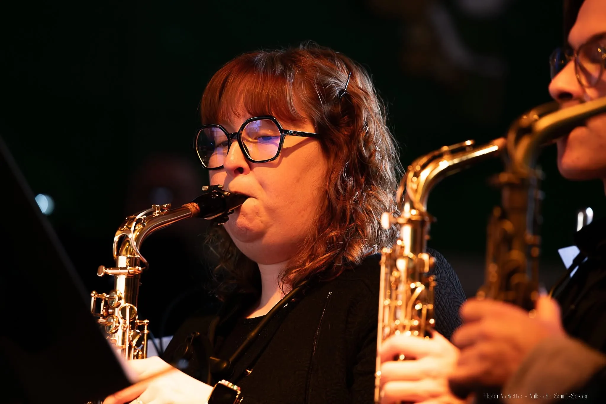 Saxophoniste alto de l'harmonie en train de jouer, éclairée d'une lumière chaude