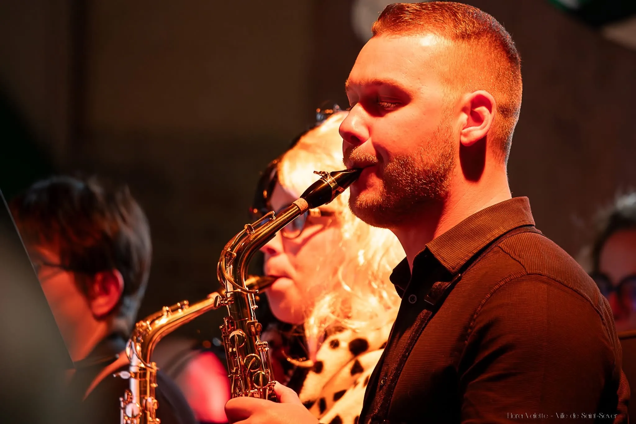 Deux saxophonistes jouant côte à côte sous une lumière orangée